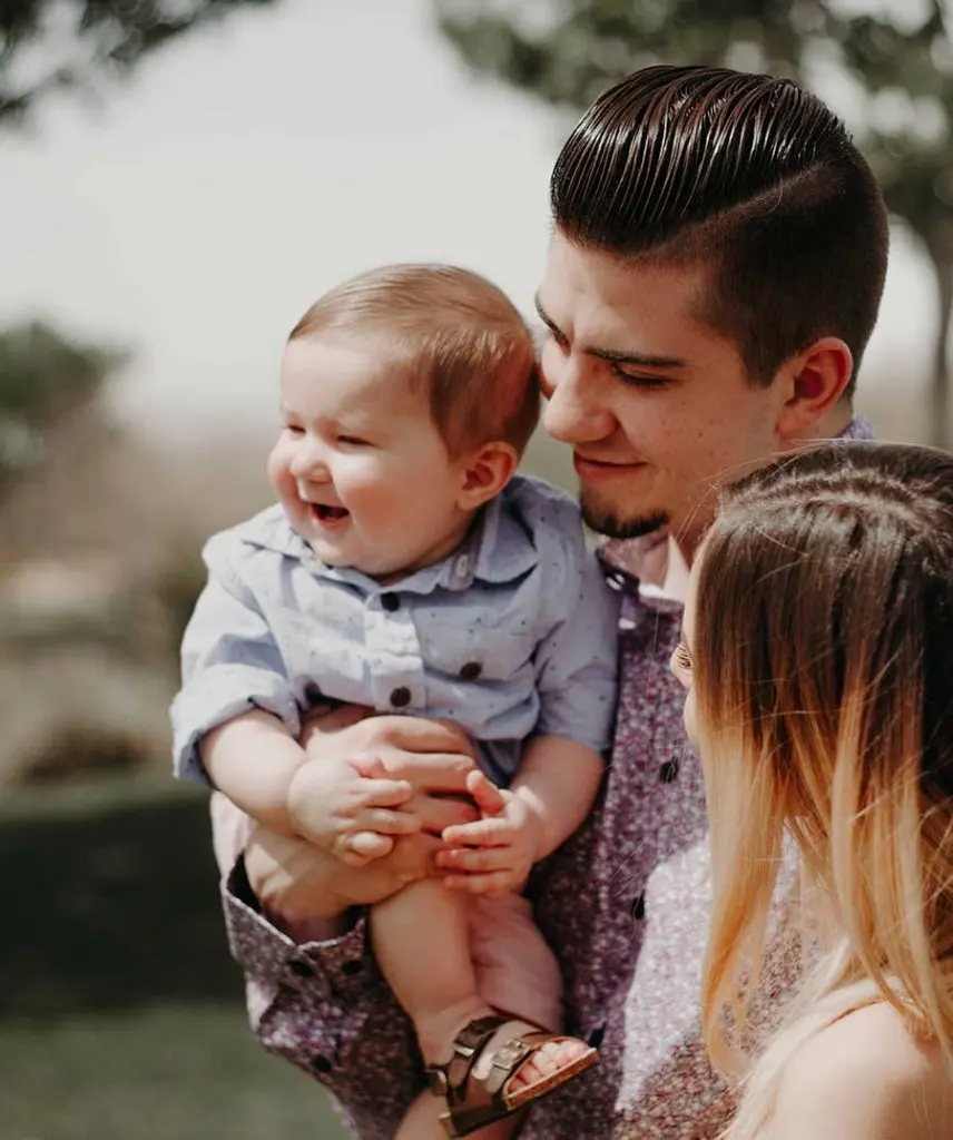 A young man and woman hold thier small child in their arms